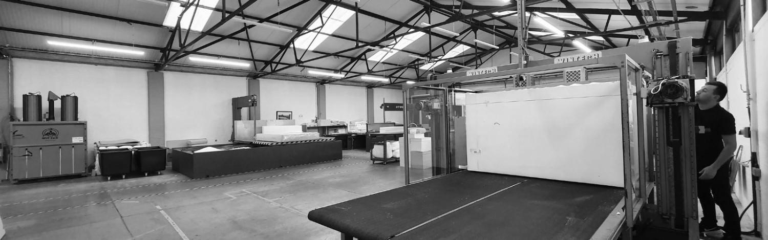 Aerofoam Ltd Wide view of foam manufacturing factory with machinery and stacked foam blocks